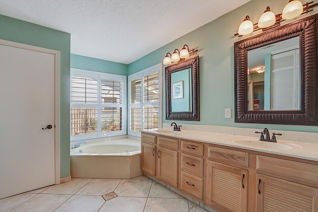 full bath featuring a textured ceiling, tile patterned flooring, a sink, and a garden tub