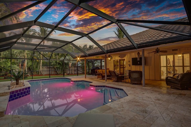 pool at dusk with ceiling fan, glass enclosure, a patio area, and fence