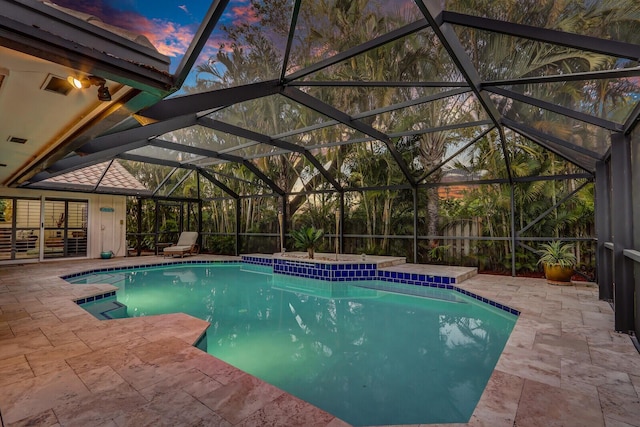 pool at dusk featuring a patio, a lanai, and an outdoor pool