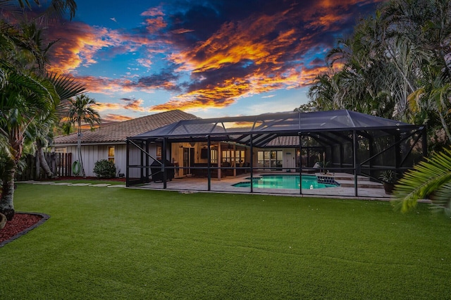 back of property at dusk featuring a patio area, fence, an outdoor pool, and a lawn