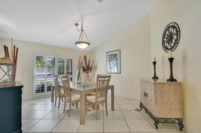 dining space featuring light tile patterned floors, baseboards, and vaulted ceiling