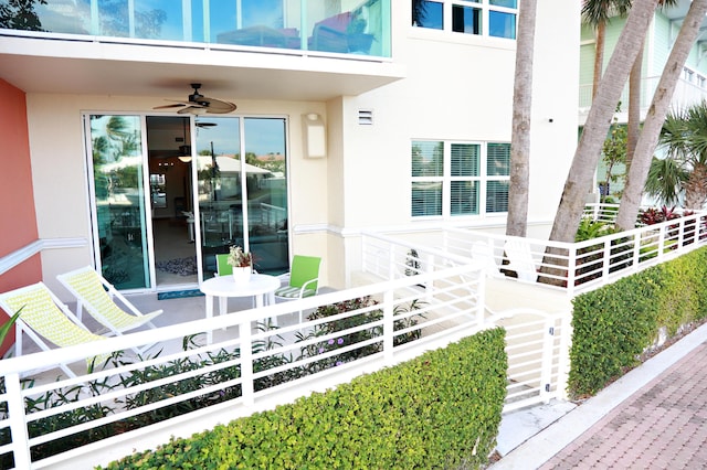 entrance to property featuring a ceiling fan and stucco siding