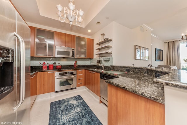 kitchen with appliances with stainless steel finishes, a chandelier, brown cabinets, and decorative backsplash