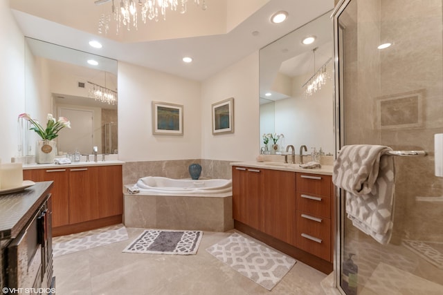 bathroom with a chandelier, two vanities, a garden tub, and a shower stall