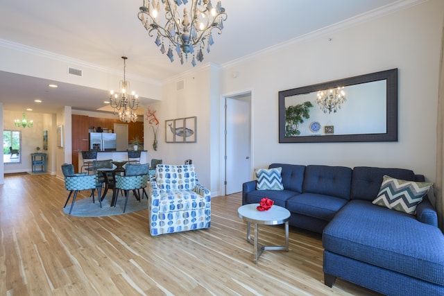 living room with crown molding, light wood-style floors, visible vents, and an inviting chandelier