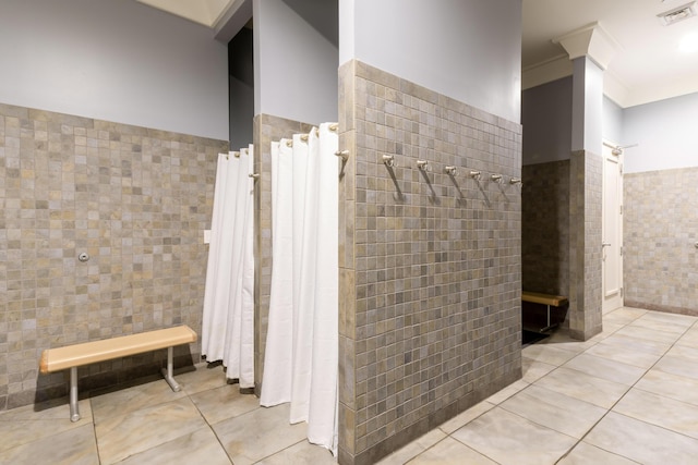 full bath with tile patterned flooring, visible vents, tile walls, ornamental molding, and a tile shower