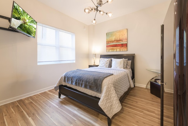 bedroom with a notable chandelier, light wood-style flooring, and baseboards