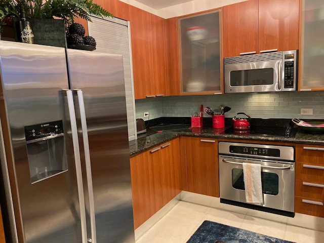 kitchen featuring brown cabinets, modern cabinets, stainless steel appliances, and decorative backsplash