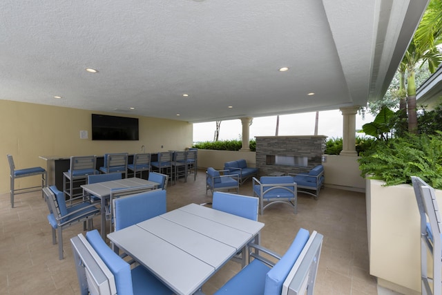 view of patio with an outdoor living space with a fireplace and outdoor dining space