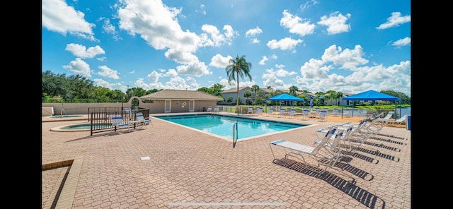 pool with a community hot tub, a patio, and fence