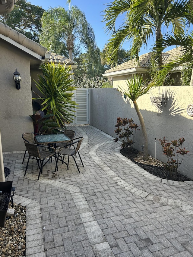 view of patio featuring outdoor dining space, fence, and a gate