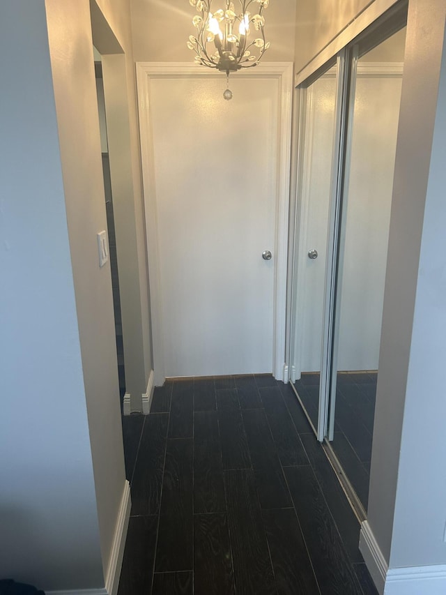 corridor with dark wood-style flooring and a notable chandelier