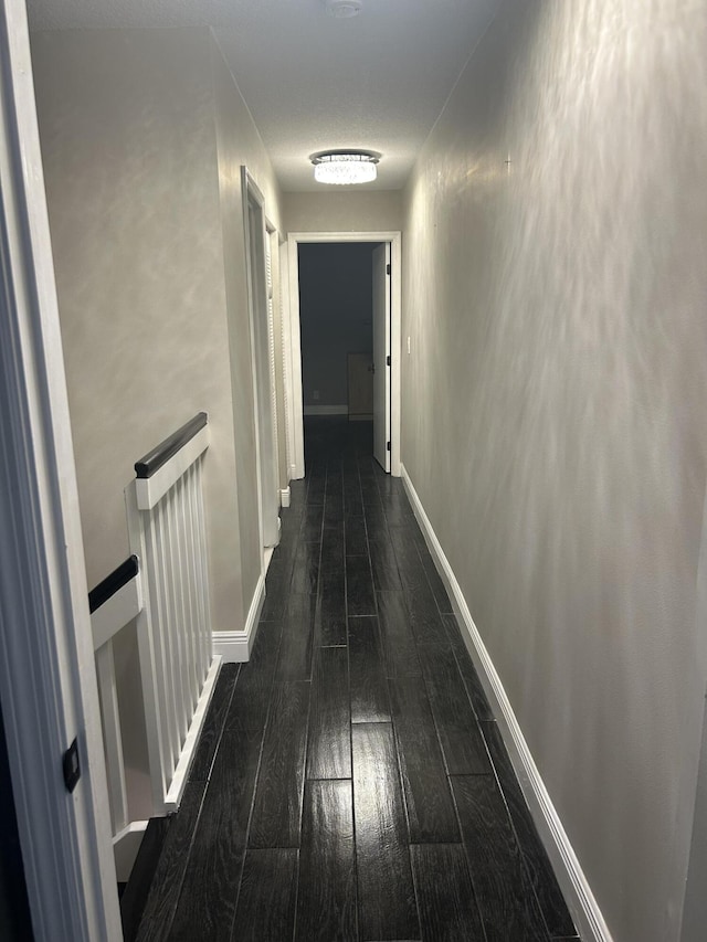 corridor featuring baseboards, hardwood / wood-style floors, and an upstairs landing