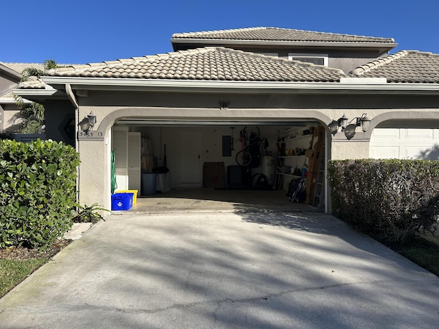 exterior space featuring electric panel, concrete driveway, a tile roof, an attached garage, and stucco siding