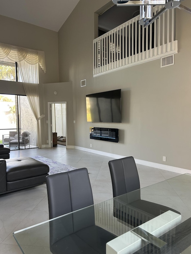 living room featuring a high ceiling, visible vents, baseboards, and tile patterned floors