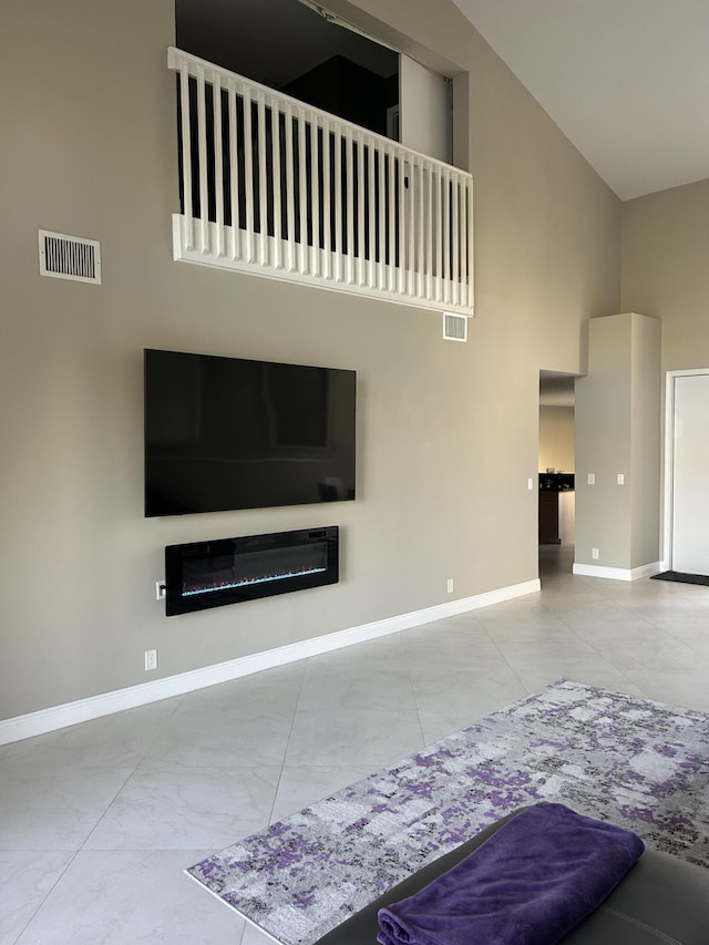 living area featuring baseboards, visible vents, and a high ceiling