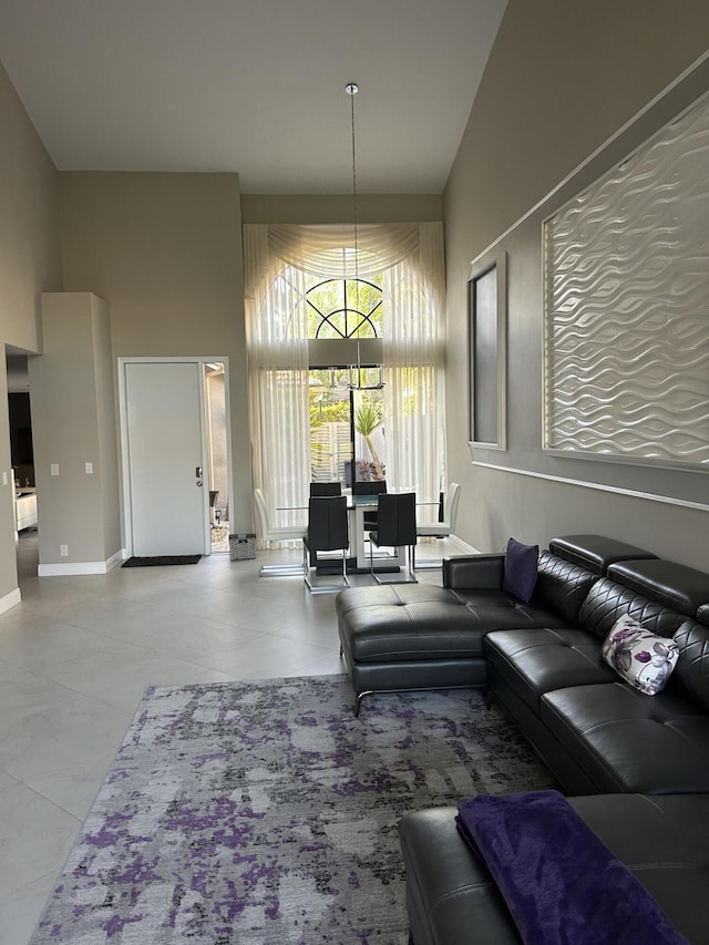 living area with baseboards, a high ceiling, and a chandelier