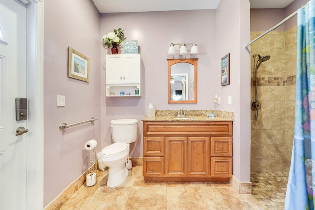 bathroom featuring a tile shower, vanity, toilet, tile patterned floors, and baseboards