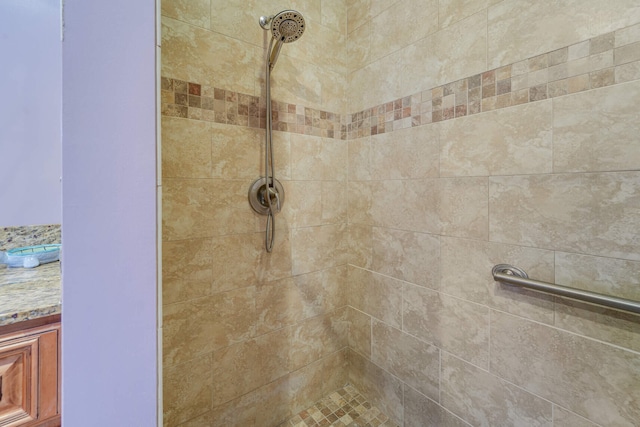 interior details featuring a tile shower and vanity