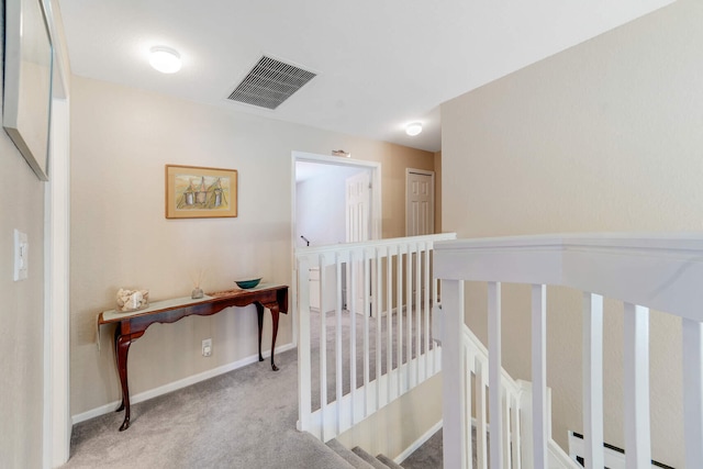 corridor featuring an upstairs landing, visible vents, baseboards, and carpet floors