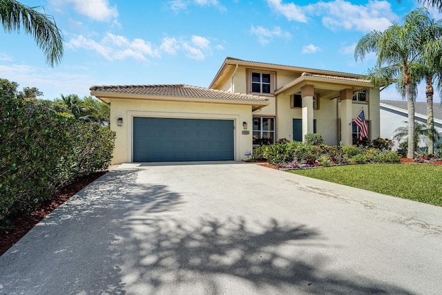 view of front of property featuring stucco siding, driveway, an attached garage, a front yard, and a tiled roof