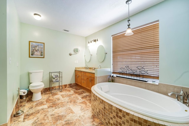 bathroom with a garden tub, vanity, visible vents, toilet, and baseboards