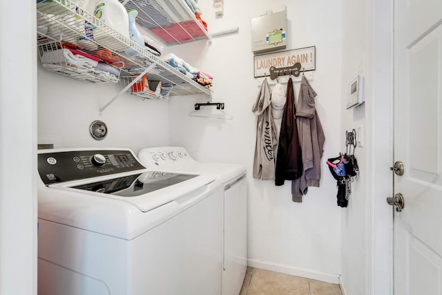 washroom featuring light tile patterned floors, baseboards, laundry area, and washing machine and clothes dryer