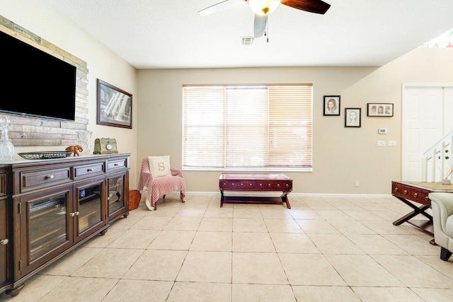 sitting room with light tile patterned floors, a ceiling fan, visible vents, and baseboards