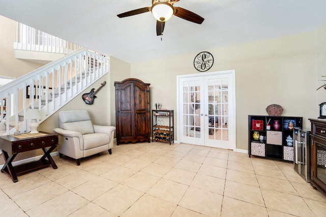 sitting room featuring french doors, a ceiling fan, light tile patterned floors, and stairs