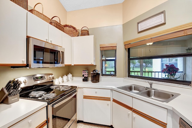 kitchen with white cabinets, appliances with stainless steel finishes, light countertops, a textured ceiling, and a sink