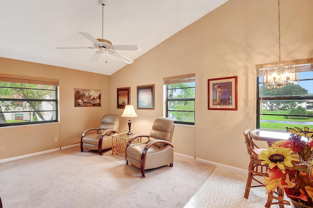 living area with high vaulted ceiling, ceiling fan with notable chandelier, baseboards, and light colored carpet