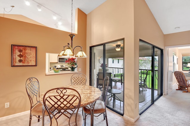 carpeted dining room featuring high vaulted ceiling, baseboards, and track lighting