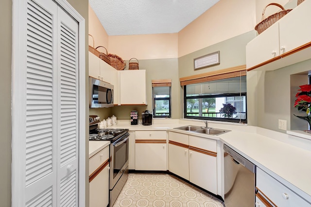 kitchen featuring light countertops, appliances with stainless steel finishes, white cabinetry, a sink, and a textured ceiling