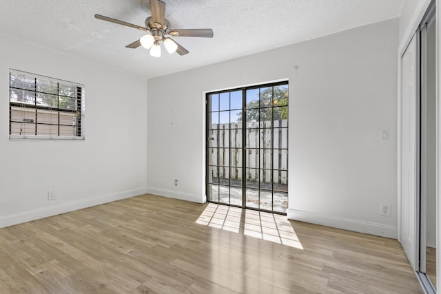 spare room featuring ceiling fan, a textured ceiling, baseboards, and wood finished floors