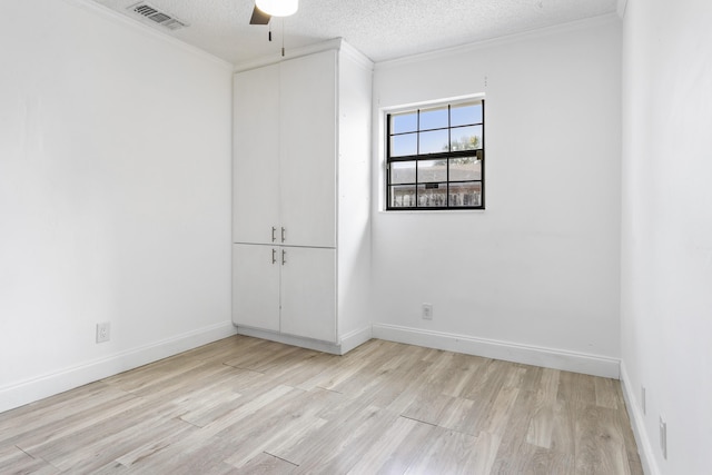 unfurnished room featuring a textured ceiling, light wood finished floors, visible vents, and baseboards