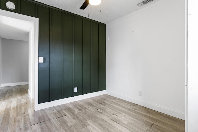 empty room featuring a textured ceiling, ceiling fan, visible vents, baseboards, and light wood-type flooring