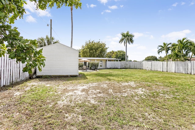 view of yard featuring an outbuilding, a patio area, a fenced backyard, and a shed