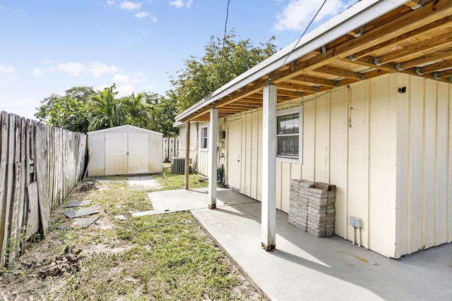 view of yard featuring a fenced backyard, cooling unit, an outdoor structure, a storage unit, and a patio area