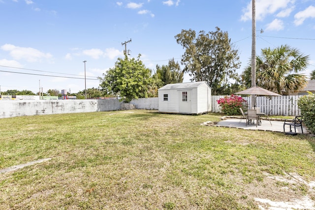 view of yard featuring a fenced backyard, a storage unit, an outbuilding, and a patio