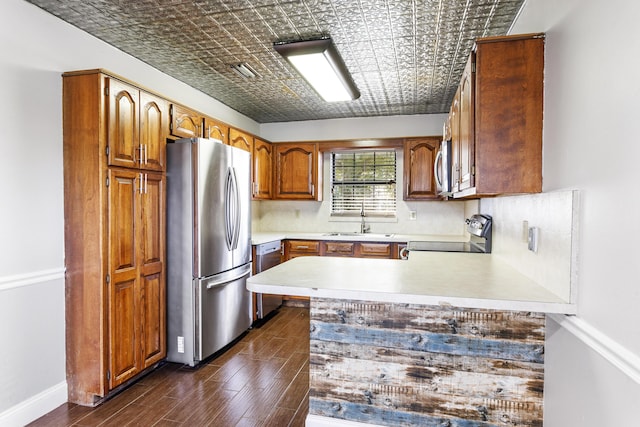 kitchen featuring stainless steel appliances, a peninsula, a sink, light countertops, and an ornate ceiling