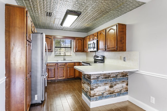 kitchen featuring stainless steel appliances, a peninsula, a sink, and an ornate ceiling