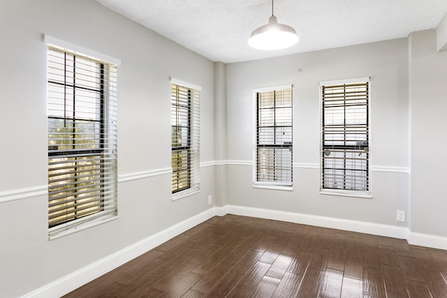 unfurnished room featuring a textured ceiling, dark wood-style flooring, and baseboards