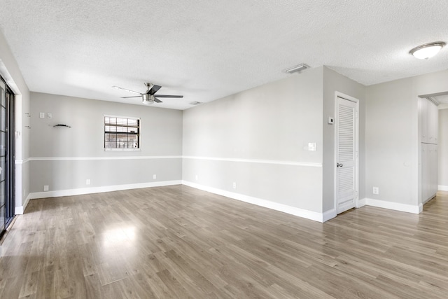 empty room with baseboards, wood finished floors, visible vents, and a ceiling fan