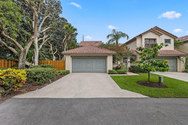 view of front facade featuring a detached garage, a tile roof, fence, stucco siding, and a front lawn