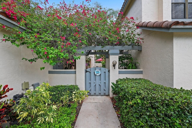 property entrance featuring a gate, a tiled roof, and stucco siding