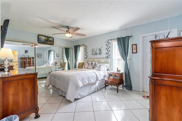 bedroom with a ceiling fan, a textured ceiling, and light tile patterned flooring