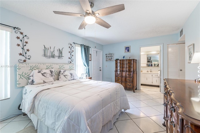 bedroom with visible vents, ensuite bathroom, light tile patterned flooring, ceiling fan, and a textured ceiling