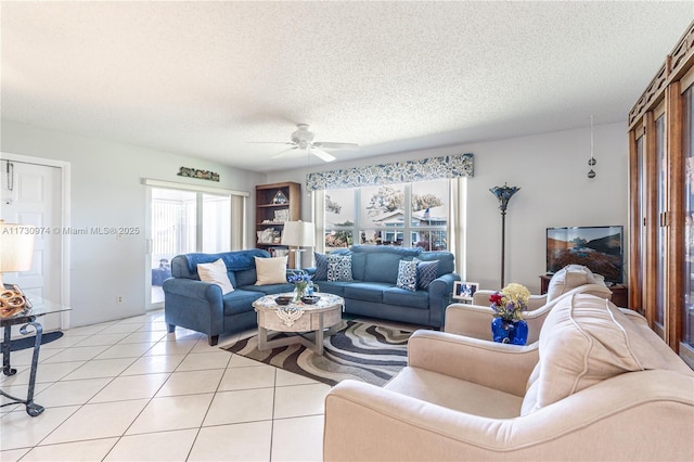 living room with a ceiling fan, a textured ceiling, and light tile patterned floors