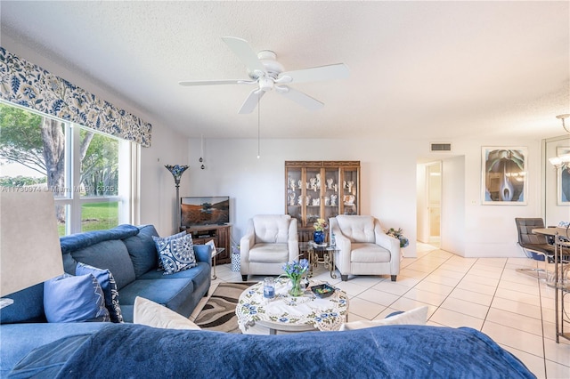 living room featuring light tile patterned floors, a textured ceiling, visible vents, and a ceiling fan