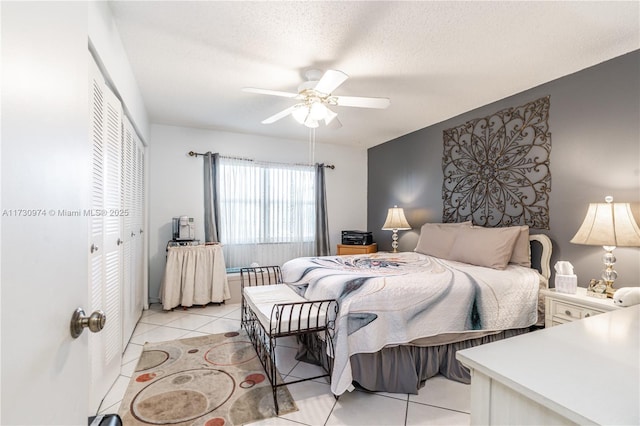 bedroom with a closet, light tile patterned flooring, ceiling fan, and a textured ceiling